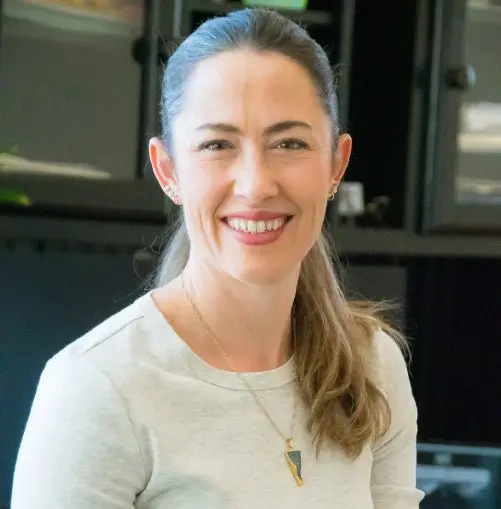 A woman standing in front of a kitchen.